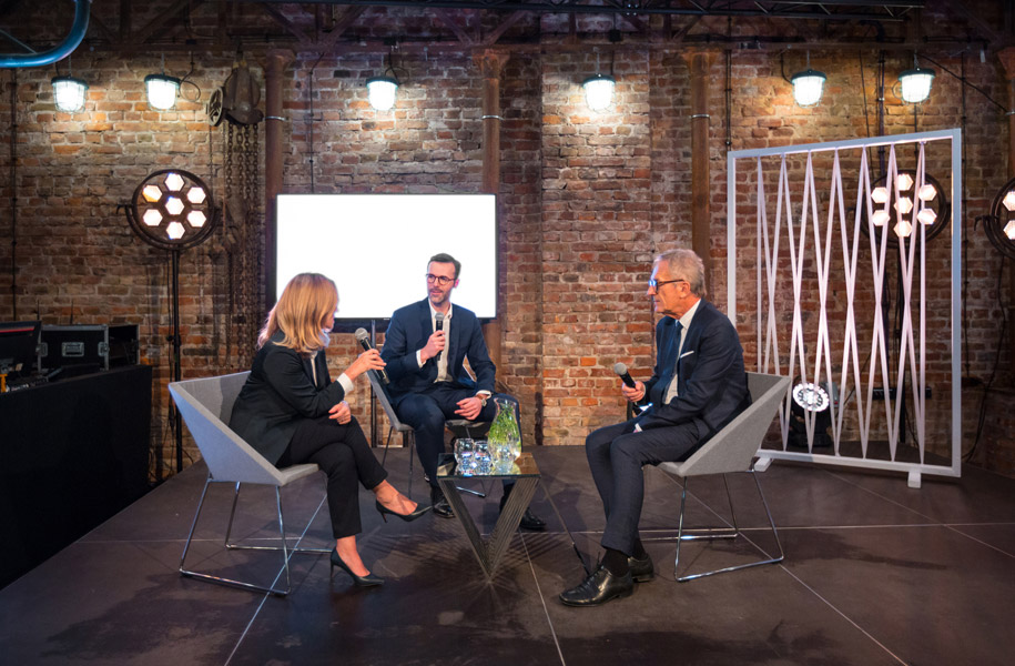 Three-business-professionals-having-a-discussion-on-stage-during-a-hybrid-event